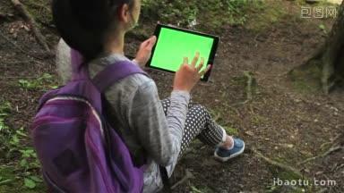 十几岁的女孩在平板电脑上搜索拷贝空间坐在森林里